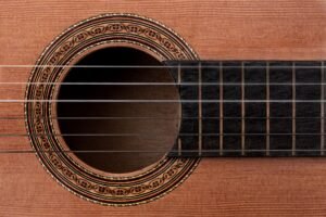 Primer plano de la tapa de una guitarra clásica: veta de la madera, boca y roseta