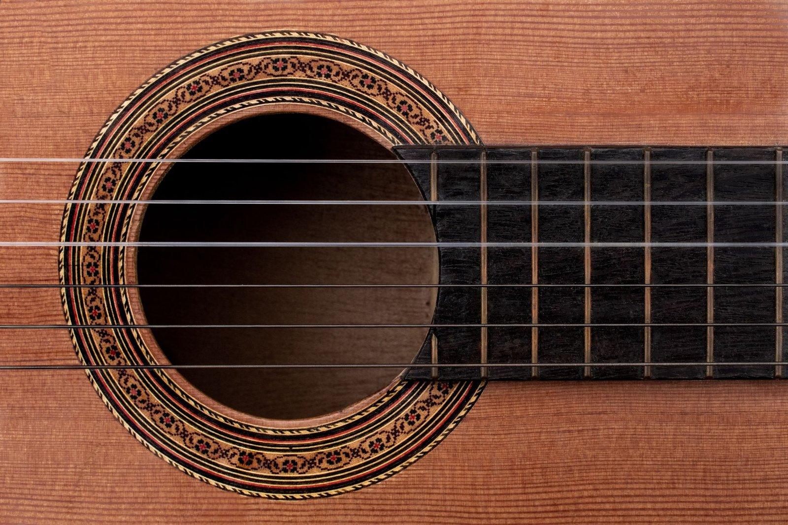Primer plano de la tapa de una guitarra clásica: veta de la madera, boca y roseta
