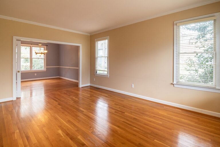 Habitación vacía con suelo de madera y ventanas grandes, ejemplo de sala doméstica antes de tratarla