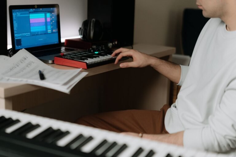 Productor usando un teclado controlador MIDI junto a un portatil en un estudio casero