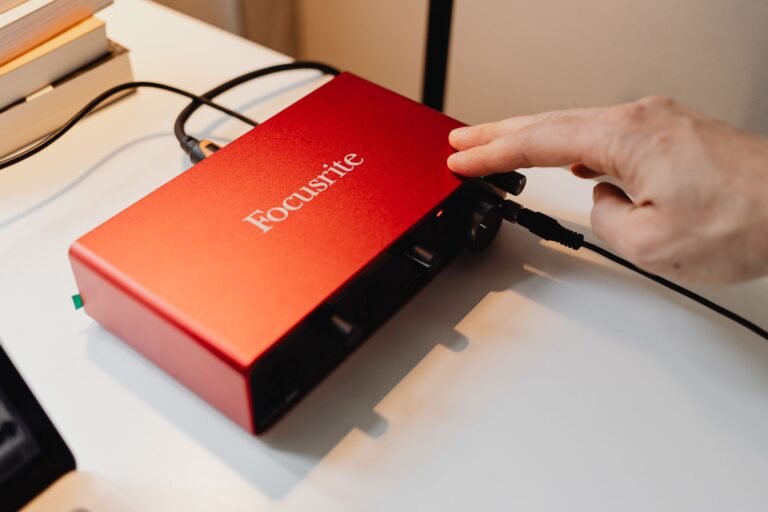 Mano ajustando los controles de ganancia de una interfaz de audio en un home studio