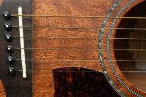 Primer plano de la tapa y las cuerdas de una guitarra acústica mostrando la veta de la madera