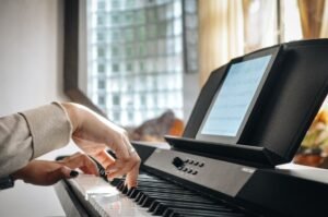 Manos tocando un piano eléctrico de teclas contrapesadas en interior