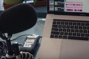 Micrófono y portátil sobre una mesa, configuración para grabar audio en casa
